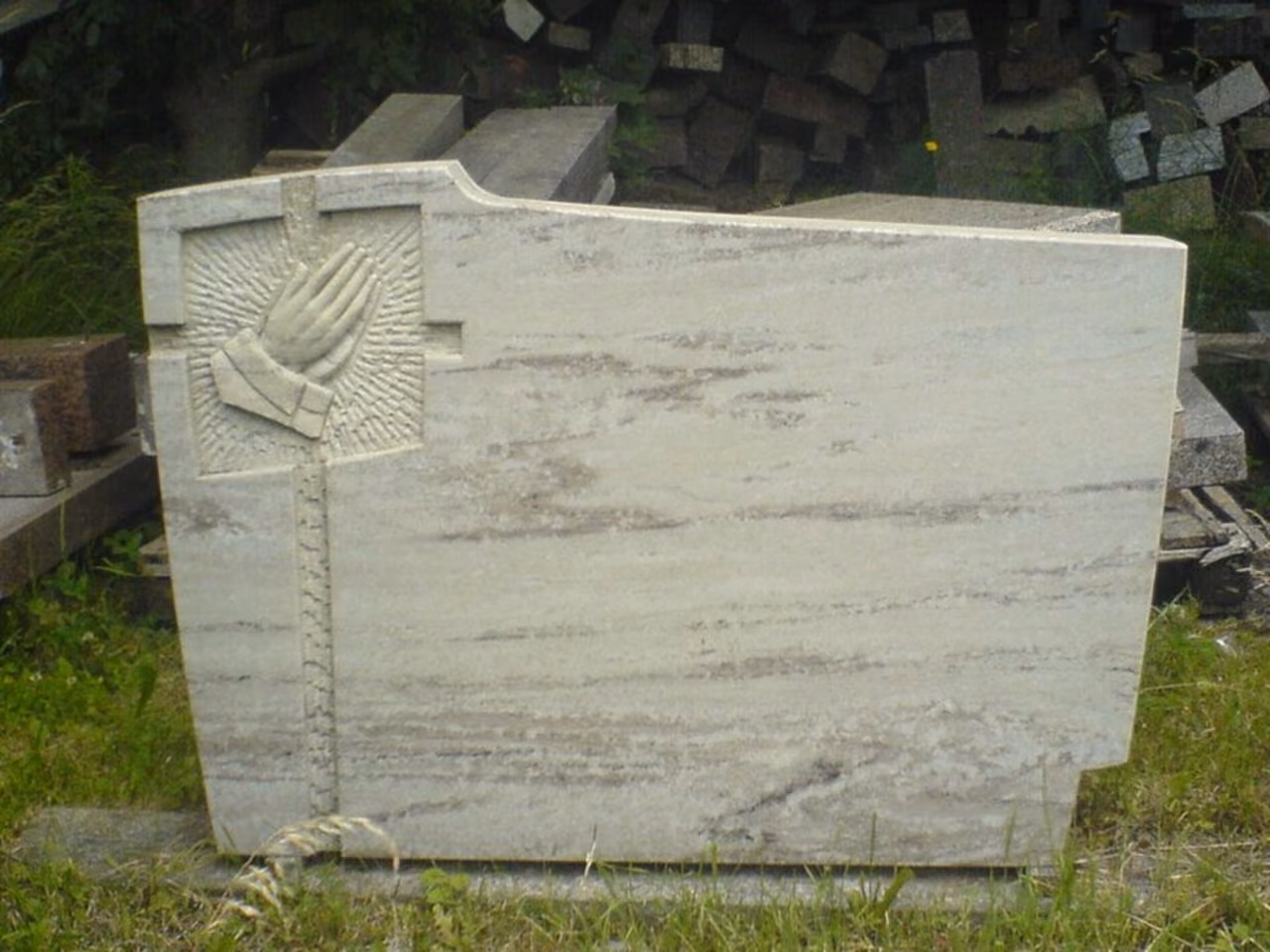 Heller Grabstein mit betenden Händen