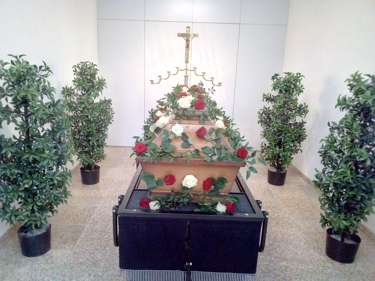 Aufgebahrter Sarg mit Rosen in einer hellen Trauerhalle